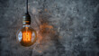 A vintage light bulb hanging from a ceiling, glowing warmly against a cool, grey background with copy space