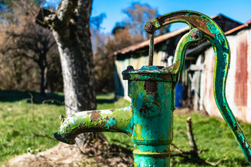 Old hand water pump on a well in the garden, watering and saving water, rural environnement