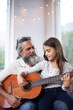 © Mikolette Moller/peopleimages.com - Mature man, girl or guitar as learning, music or training as creative practice for skill development. Retired teacher, student or instrument to mentor, guide or advice as song, bonding or together