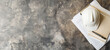 Top-view of hard hat, clipboard, and pen on a grungy concrete surface, symbolizing construction planning. Banner with copy space