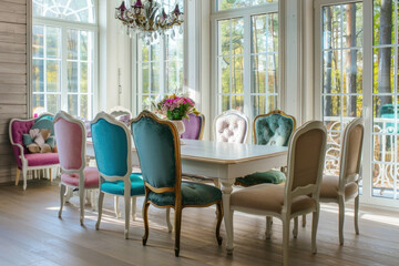 Wall Mural - Rustic, vintage furniture, table and chairs of various bright colors in the dining room with large windows.