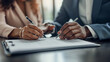Two individuals engaged in signing a document, which is indicative of a business agreement or contract being formalized.