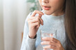 © Pormezz - Dietary supplement, asian young woman, girl hand holding orange medical pill, take or eat vitamin C, D for treatment for skin