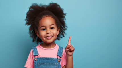 Wall Mural - young African American girl with a big smile, wearing a pink shirt and a blue denim jumper, set against a light blue background