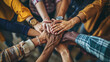 © Studio Nova - A top-down view of a group of friends stacking their hands together, symbolizing unity, teamwork, and mutual support in a casual setting.