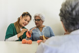 Young Asian care taker teaching eldery Indian woman crocheting in senior homecare