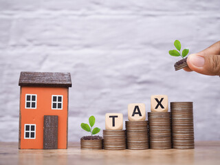 Poster - Miniature house and Wooden blocks with the word TAX on stack of coins. The concept of payment tax for house, Property investment, House mortgage, Real estate