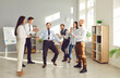 © Studio Romantic - Group of happy funny young business people company employees having fun organizing competitions between coworkers in office with a stick. Teamwork, corporate team building and success concept.