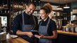 © Studio Nova - Cafe worker and manager smiling and engaging with each other while using a tablet