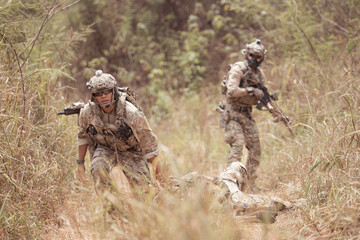 Wall Mural - Soldiers in camouflage military uniforms carrying weapons, Reconnaissance missions in the tropical forest area with mission of helping those injured from being shot