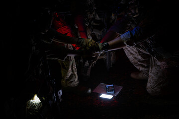 Wall Mural - Group of soldiers in camouflage uniforms hold weapons with patrol missions at night