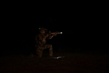 Soldiers in camouflage uniforms hold weapons with patrol missions at night