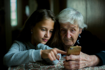 Wall Mural - A girl teaches her grandmother how to use her smartphone.