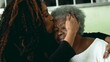 © Marco - Tender loving moment of African American adult daughter kissing elderly 80s senior mother in the forehead and posing close-up faces smiling at camera