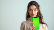 Photo of a woman holding up a phone with a green screen, white background, a stock photo