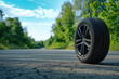 summer tire ad image on alloy wheel rim, tyre on summer highway with copy space on green forest