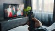 hand of a man holding a remote control while watching tv