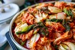 A top-down view of a diverse selection of kimchi varieties in a colorful bowl, showcasing cabbage, radish, scallions, and other ingredients on a table