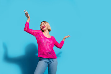 Poster - Photo portrait of lovely young lady raise hands dancing dressed stylish pink knitwear garment isolated on blue color background