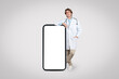 © Prostock-studio - Smiling male doctor leaning on giant smartphone blank screen