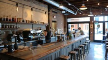 Rustic Coffee Shop Interior With Brick Walls, Wooden Tables And Chairs, And A Large Coffee Bar. A Barista Is Making Coffee Behind The Counter.