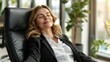 Smiling businesswoman sitting in office chair relaxing with eyes closed,