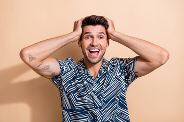 Poster - Photo of impressed man with tattoos dressed print shirt keep hands on head staring at unbelievable sale isolated on beige color background