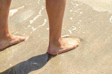 legs of a woman on the shore of a beach in summertime, holidays concept