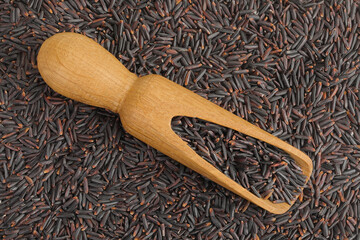 Poster - Black rice in a wooden scoop as a background. Top view. Flat lay