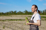 Fototapeta  - Happy farmer with bunch of green asparagus on field background