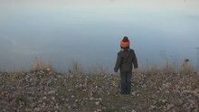 Boy on lake shore throws stones in water