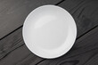 A white plate with a slight smudge on a dark wooden surface