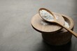Baking powder in bowl and spoon on grey textured table, space for text