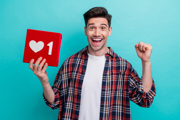 Canvas Print - Photo of positive lucky man dressed plaid shirt rising fist holding heart like feedback heart isolated turquoise color background