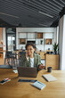 © Viktoria Kovalchuk - A woman seated at a desk with a laptop, talking on a cell phone in nice modern coworking office