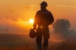 A single worker, silhouetted against the dawn light, holding a helmet under one arm, symbolizing the dignity of labor on International Labour Day.