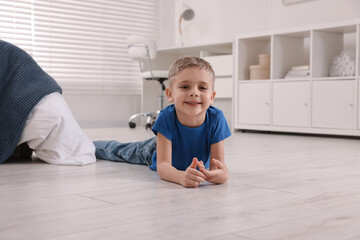 Canvas Print - Cute little boy lying on warm floor at home. Heating system