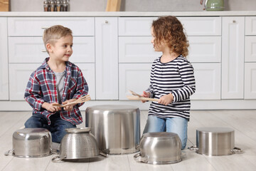 Wall Mural - Little children pretending to play drums on pots in kitchen