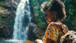 Adventurous African American Woman Journaling Her Travels by a Waterfall. Concept of Adventure, Reflection, and Nature.