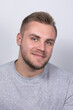 © Iuliia - A smiling young blond man with a beard wearing a gray shirt