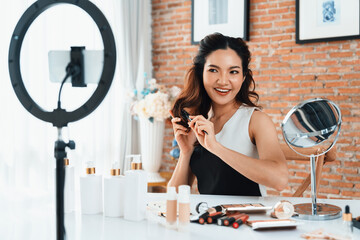 Wall Mural - Asian Woman influencer shoot live streaming vlog video review makeup uttermost social media or blog. Happy young girl with cosmetics studio lighting for marketing recording session broadcasting online