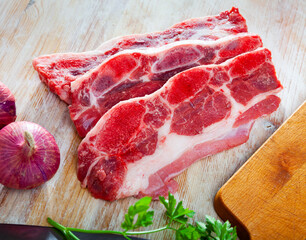 Wall Mural - Raw beef with streaks of fat on kitchen table with red onion, garlic and parsley