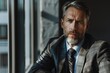 © pham - A mature middle-aged businessman in a suit and tie standing by the window, gazing outside