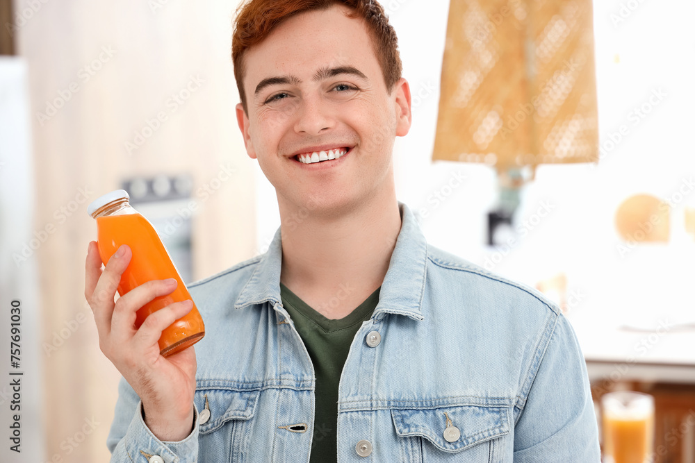Young man with bottle of juice in kitchen, closeup