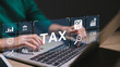 © FAMILY STOCK - A person is typing on a laptop with a screen that says Tax