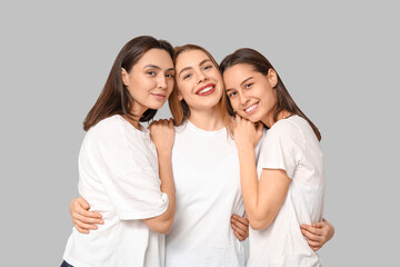 Poster - Portrait of beautiful hugging women on grey background. Women history month