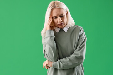 Sticker - Mature woman suffering from headache on green background