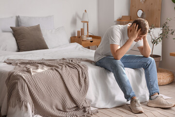 Wall Mural - Young man suffering from headache in bedroom