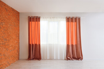 Red curtains on large window in empty living room