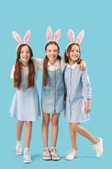 Wall Mural - Cute little girls with Easter bunny ears on blue background